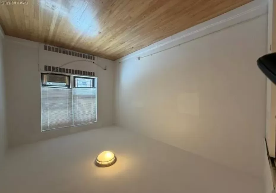 Wood-finish flooring, white walls, and a window with blinds Wood-finish flooring, white walls, and a window with blinds