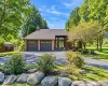 Property exterior featuring a multi-car garage, brick facade accents, a prominent front entrance with transom windows, and mature trees Property exterior featuring a multi-car garage, brick facade accents, a prominent front entrance with transom windows, and mature trees