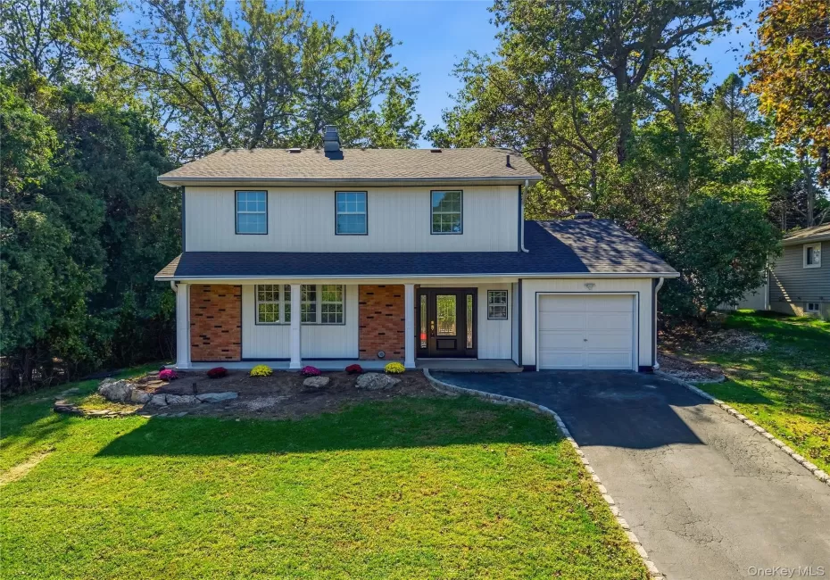 Two-story exterior with white siding and brick accents, featuring a front porch with white columns, an attached single-car garage, and a paved driveway Two-story exterior with white siding and brick accents, featuring a front porch with white columns, an attached single-car garage, and a paved driveway