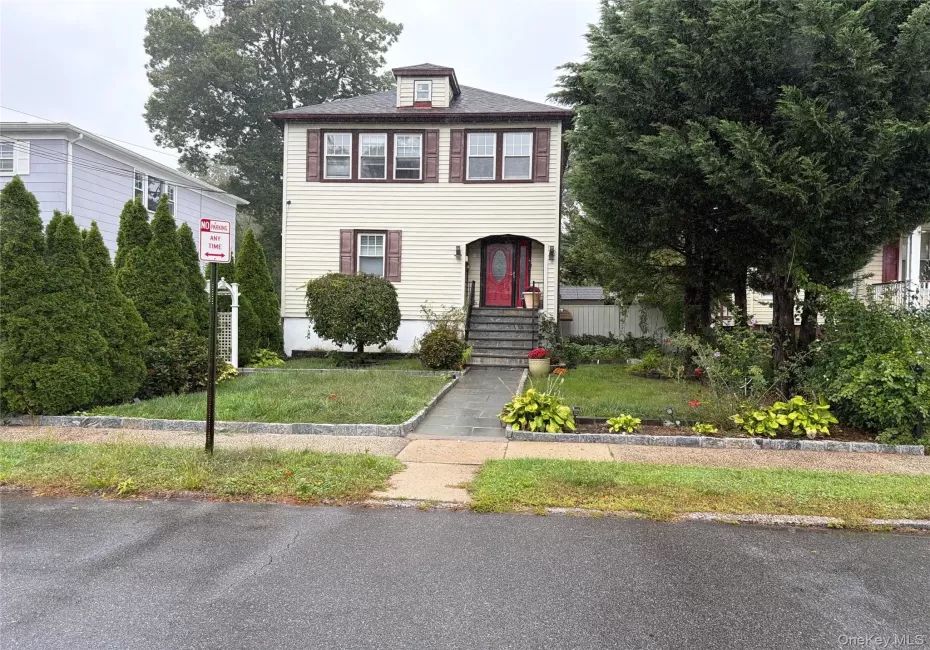 Two-story residence with dormer, prominent red entry door, and stone steps Two-story residence with dormer, prominent red entry door, and stone steps
