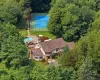 Tudor-style residence set amidst lush trees, featuring mahogany decking, stone patio, tennis court, and swimming pool. Tudor-style residence set amidst lush trees, featuring mahogany decking, stone patio, tennis court, and swimming pool.