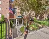Brick facade building with a prominent entrance featuring a green domed awning, glass entry doors, a concrete ramp, and landscaped planters Brick facade building with a prominent entrance featuring a green domed awning, glass entry doors, a concrete ramp, and landscaped planters