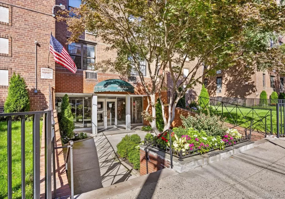 Brick facade building with a prominent entrance featuring a green domed awning, glass entry doors, a concrete ramp, and landscaped planters Brick facade building with a prominent entrance featuring a green domed awning, glass entry doors, a concrete ramp, and landscaped planters