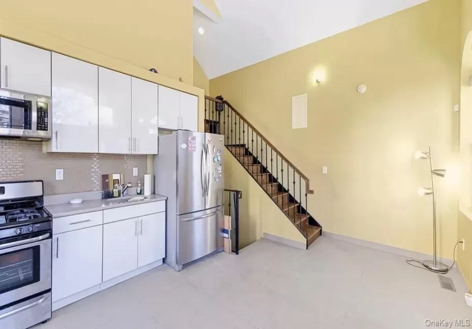 Kitchenette featuring stainless steel appliances, white cabinetry, and light-toned flooring Kitchenette featuring stainless steel appliances, white cabinetry, and light-toned flooring