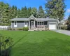 Shingle siding exterior with stone accents, a covered front porch, an attached garage, a paved driveway, and a front lawn Shingle siding exterior with stone accents, a covered front porch, an attached garage, a paved driveway, and a front lawn