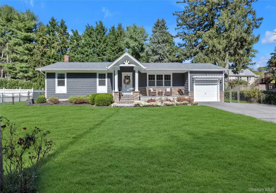 Shingle siding exterior with stone accents, a covered front porch, an attached garage, a paved driveway, and a front lawn Shingle siding exterior with stone accents, a covered front porch, an attached garage, a paved driveway, and a front lawn