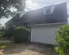 Stone-clad exterior with dormer windows, attached garage, concrete driveway, and established landscaping Stone-clad exterior with dormer windows, attached garage, concrete driveway, and established landscaping