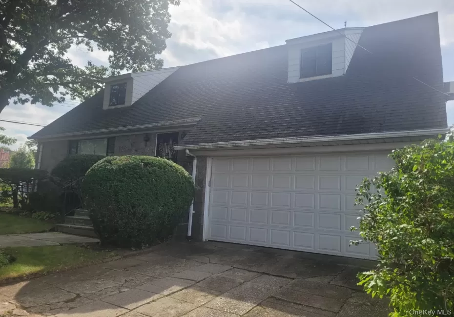 Stone-clad exterior with dormer windows, attached garage, concrete driveway, and established landscaping Stone-clad exterior with dormer windows, attached garage, concrete driveway, and established landscaping
