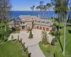 Brick exterior with a multi-car garage, expansive manicured lawn, gravel circular driveway, and mature landscaping Brick exterior with a multi-car garage, expansive manicured lawn, gravel circular driveway, and mature landscaping