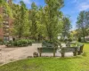 Landscaped courtyard featuring mature trees, green lawn, paved walking paths, and multiple park benches Landscaped courtyard featuring mature trees, green lawn, paved walking paths, and multiple park benches