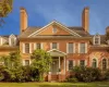 Colonial house with brick siding, a chimney, and a front lawn Colonial house with brick siding, a chimney, and a front lawn