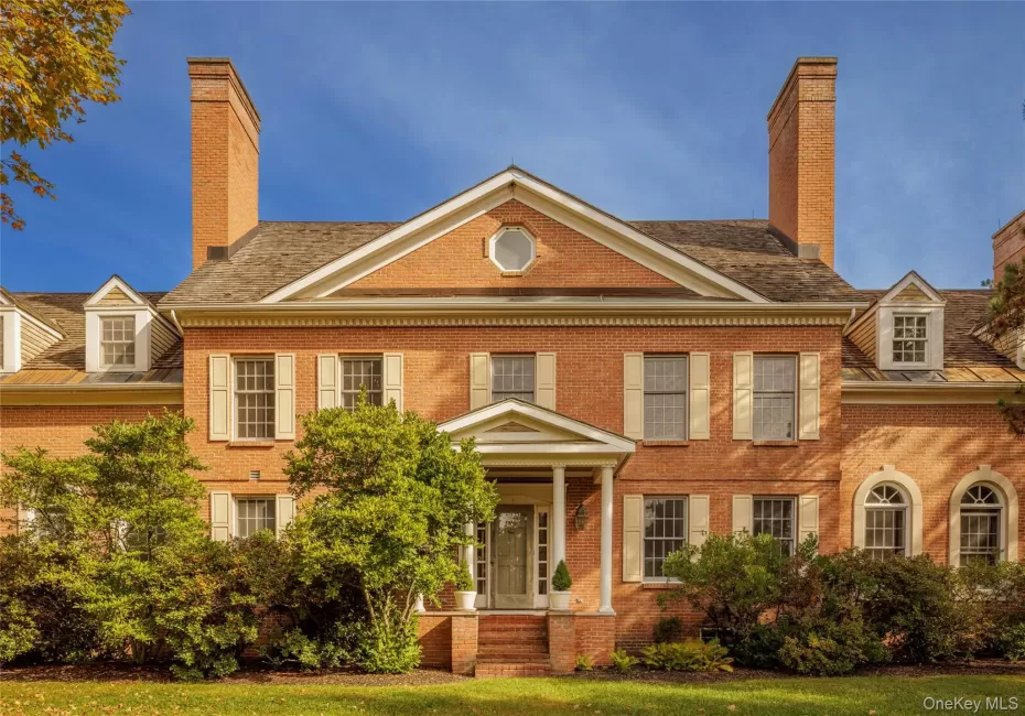 Colonial house with brick siding, a chimney, and a front lawn Colonial house with brick siding, a chimney, and a front lawn