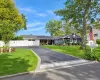 Expansive paved driveway with paver stone accent, white privacy fence, manicured lawn, and mature trees Expansive paved driveway with paver stone accent, white privacy fence, manicured lawn, and mature trees