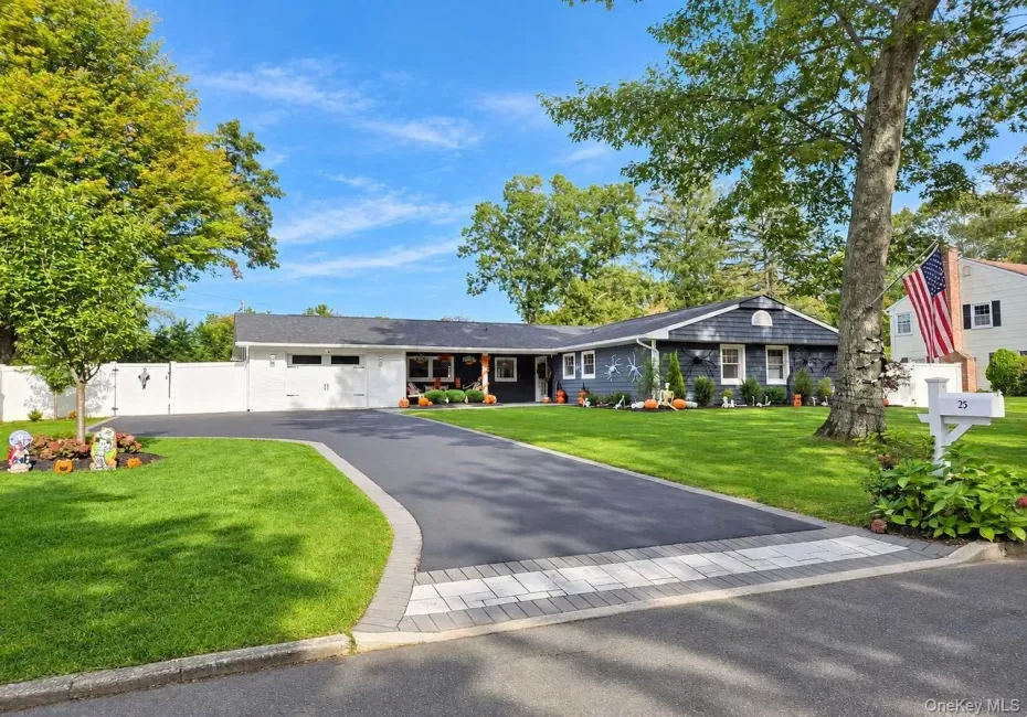 Expansive paved driveway with paver stone accent, white privacy fence, manicured lawn, and mature trees Expansive paved driveway with paver stone accent, white privacy fence, manicured lawn, and mature trees