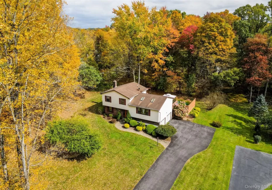 Split-level residence featuring a multi-tone exterior, asphalt driveway, two attached garage bays, roof-mounted skylights, and a wood privacy fence Split-level residence featuring a multi-tone exterior, asphalt driveway, two attached garage bays, roof-mounted skylights, and a wood privacy fence