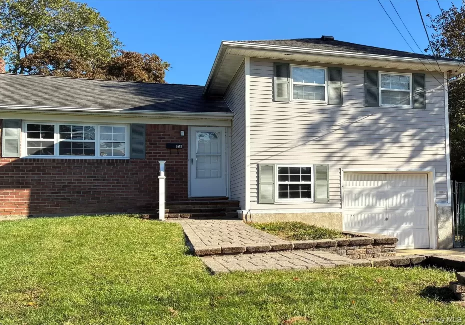 Brick and siding exterior with a shingled roof, featuring a paver walkway and an integrated garage Brick and siding exterior with a shingled roof, featuring a paver walkway and an integrated garage