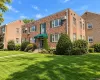 Multi-story brick exterior featuring green shutters, a covered entryway with a matching fabric awning, and manicured landscaping Multi-story brick exterior featuring green shutters, a covered entryway with a matching fabric awning, and manicured landscaping