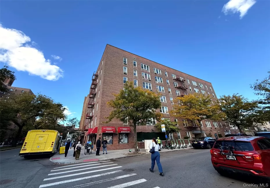 Multi-story brick exterior building featuring a corner lot orientation, integrated fire escapes, and ground-level commercial space with red awnings Multi-story brick exterior building featuring a corner lot orientation, integrated fire escapes, and ground-level commercial space with red awnings