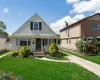 Gable-roof exterior featuring light-toned horizontal siding, arched entryway, multi-pane front windows, and a paved private driveway Gable-roof exterior featuring light-toned horizontal siding, arched entryway, multi-pane front windows, and a paved private driveway