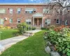 Brick exterior building with a covered entryway, concrete steps, white metal railings, and landscaped grounds featuring mature greenery Brick exterior building with a covered entryway, concrete steps, white metal railings, and landscaped grounds featuring mature greenery