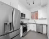 Kitchen featuring white shaker-style cabinetry, solid-surface countertops, subway tile backsplash, stainless steel appliances, and large-format tile flooring Kitchen featuring white shaker-style cabinetry, solid-surface countertops, subway tile backsplash, stainless steel appliances, and large-format tile flooring