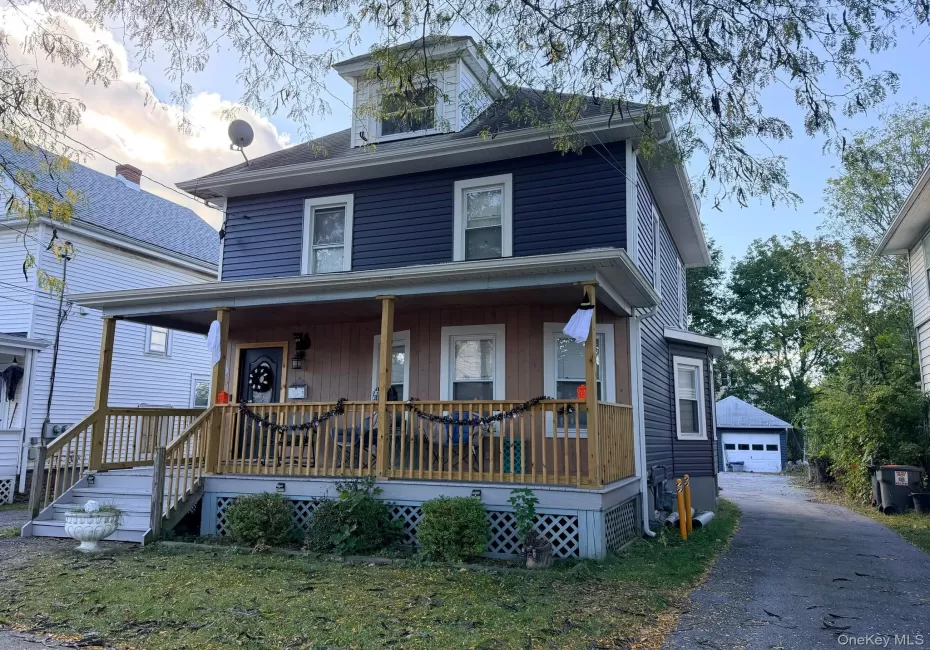 Two-story structure with blue siding, a covered front porch featuring wood-finish railings, and a dormer window Two-story structure with blue siding, a covered front porch featuring wood-finish railings, and a dormer window
