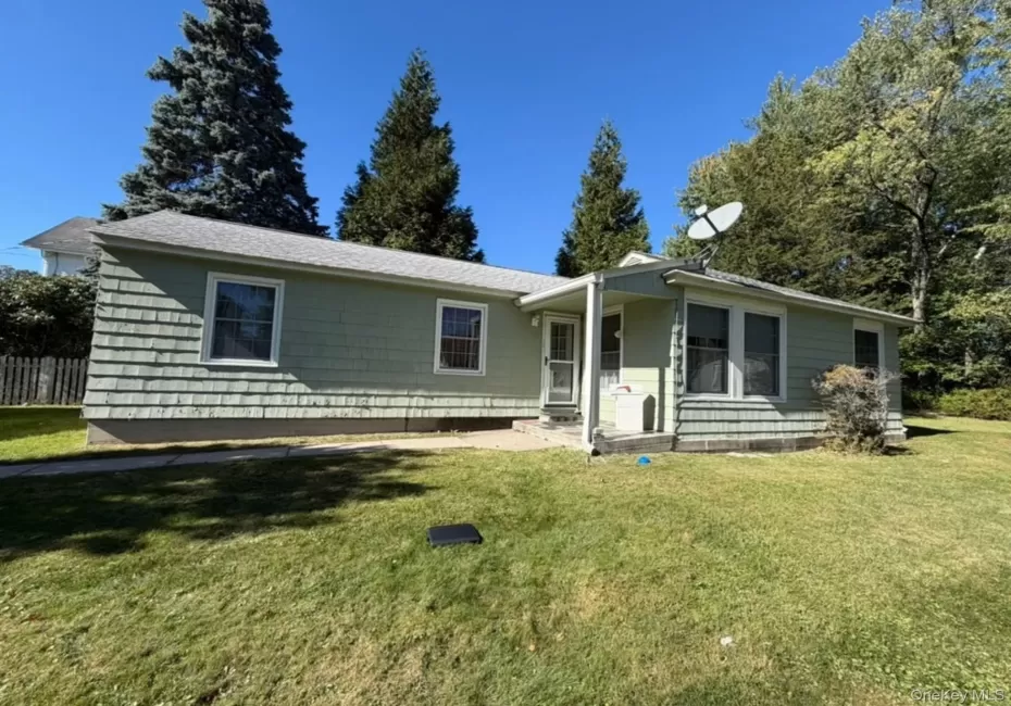 Light green shingle siding, multiple windows, and a paved walkway Light green shingle siding, multiple windows, and a paved walkway