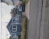Dark-toned horizontal siding exterior featuring a front-facing wood deck with white railings, a detached garage, and a concrete driveway Dark-toned horizontal siding exterior featuring a front-facing wood deck with white railings, a detached garage, and a concrete driveway