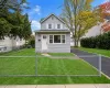 Two-story home with grey vinyl siding, white trim, a multi-pane front entry door, a paved driveway, and a chain-link fenced front yard *lawn and fence virtually edited Two-story home with grey vinyl siding, white trim, a multi-pane front entry door, a paved driveway, and a chain-link fenced front yard *lawn and fence virtually edited