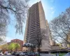 High-rise building exterior featuring a light-toned brick facade, curved balcony tiers, and a covered entrance canopy High-rise building exterior featuring a light-toned brick facade, curved balcony tiers, and a covered entrance canopy