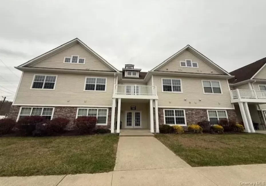 View of front of property featuring a front lawn, a balcony, driveway, and covered porch View of front of property featuring a front lawn, a balcony, driveway, and covered porch