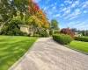 Brick exterior featuring a paved stone driveway, manicured landscaping, mature trees, and bay windows Brick exterior featuring a paved stone driveway, manicured landscaping, mature trees, and bay windows