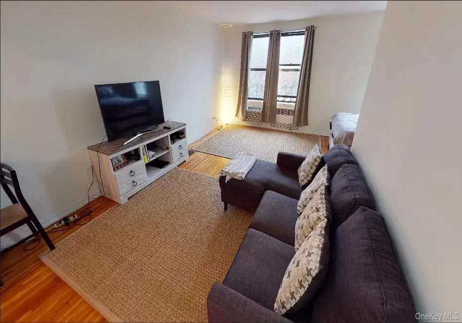 Living area featuring wood-finish flooring and three windows with metal frames Living area featuring wood-finish flooring and three windows with metal frames