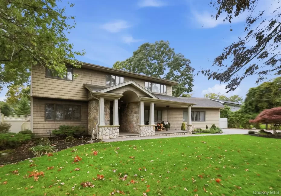 Exterior facade featuring stone veneer detailing, shingle-style siding, a covered entryway with column supports, and a paved walkway Exterior facade featuring stone veneer detailing, shingle-style siding, a covered entryway with column supports, and a paved walkway