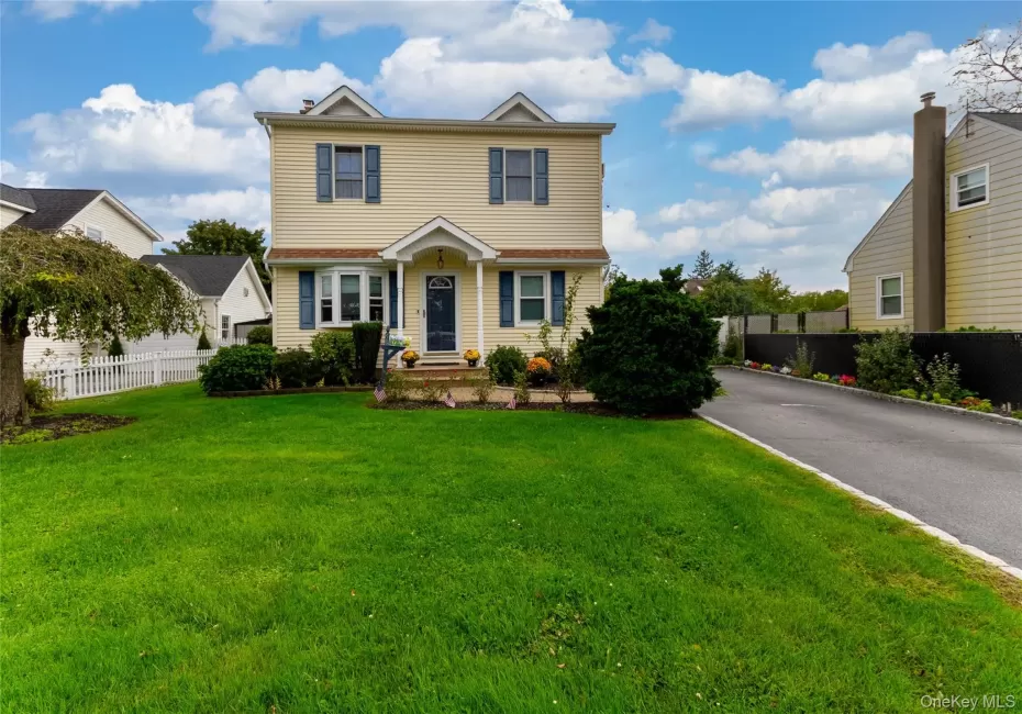 Two-story residence with dormer windows, a covered front entry, and a paved driveway Two-story residence with dormer windows, a covered front entry, and a paved driveway