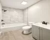 Full bathroom featuring large-format wall tiling in the shower surround, wood-finish flooring, a grey vanity with a white countertop, and matte black plumbing fixtures Full bathroom featuring large-format wall tiling in the shower surround, wood-finish flooring, a grey vanity with a white countertop, and matte black plumbing fixtures