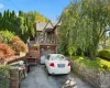 Brick exterior with stone accents, arched entryway, balcony with metal railing, attached garage, and stone retaining wall Brick exterior with stone accents, arched entryway, balcony with metal railing, attached garage, and stone retaining wall