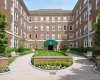 Brick exterior façade featuring a central courtyard, paved walkway, manicured lawn, and professional landscaping Brick exterior façade featuring a central courtyard, paved walkway, manicured lawn, and professional landscaping