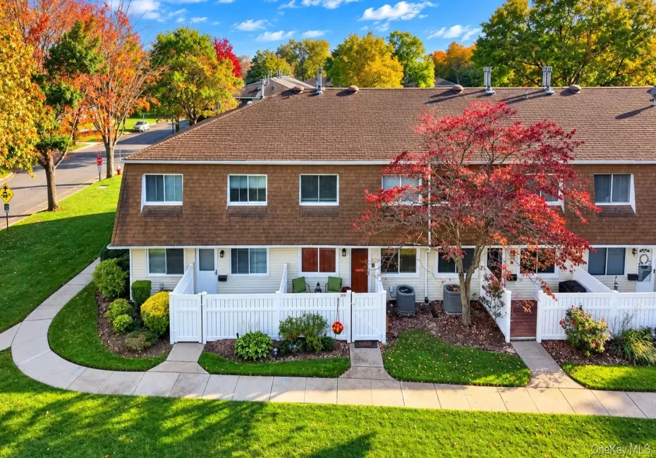 Multi-level exterior featuring light-toned siding, asphalt shingle roofing, white privacy fencing, and concrete walkways Multi-level exterior featuring light-toned siding, asphalt shingle roofing, white privacy fencing, and concrete walkways