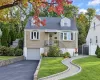 Stone exterior featuring dual dormer windows, a covered front entry with wrought-iron railing, an attached garage, and a paver stone walkway Stone exterior featuring dual dormer windows, a covered front entry with wrought-iron railing, an attached garage, and a paver stone walkway
