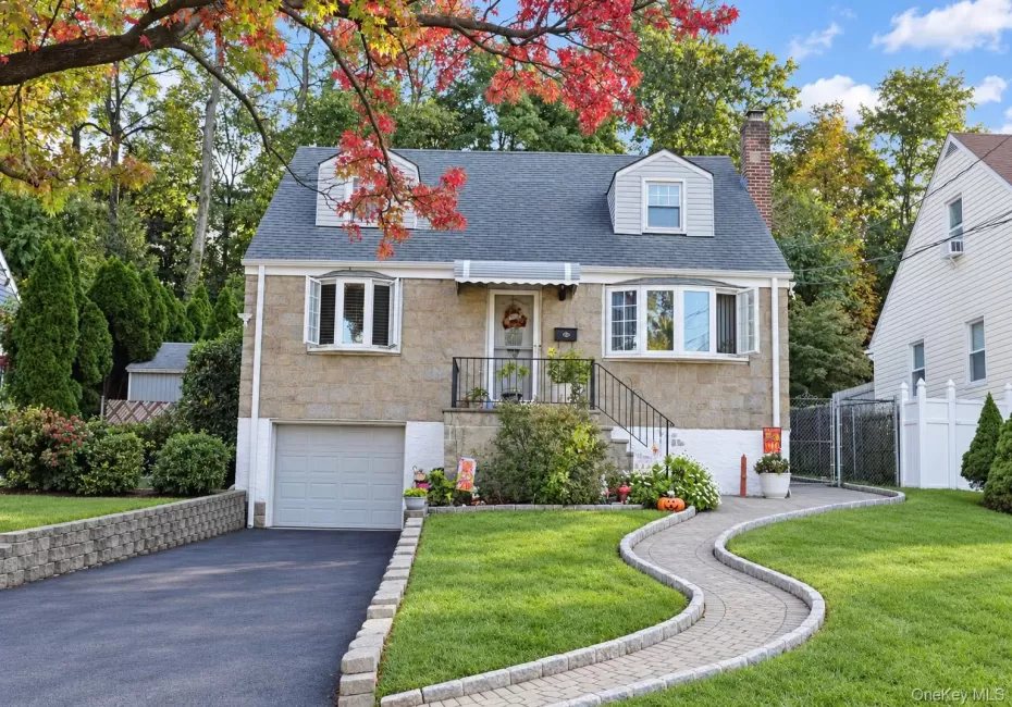 Stone exterior featuring dual dormer windows, a covered front entry with wrought-iron railing, an attached garage, and a paver stone walkway Stone exterior featuring dual dormer windows, a covered front entry with wrought-iron railing, an attached garage, and a paver stone walkway
