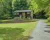 Two-story residence featuring wood-shake siding, shuttered windows, an asphalt driveway, and a tiered brick retaining wall Two-story residence featuring wood-shake siding, shuttered windows, an asphalt driveway, and a tiered brick retaining wall