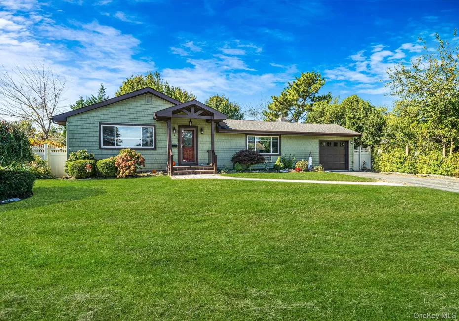 Single-story exterior featuring shake-style siding, an expansive front lawn, a covered entryway with timber detailing, and an attached garage Single-story exterior featuring shake-style siding, an expansive front lawn, a covered entryway with timber detailing, and an attached garage