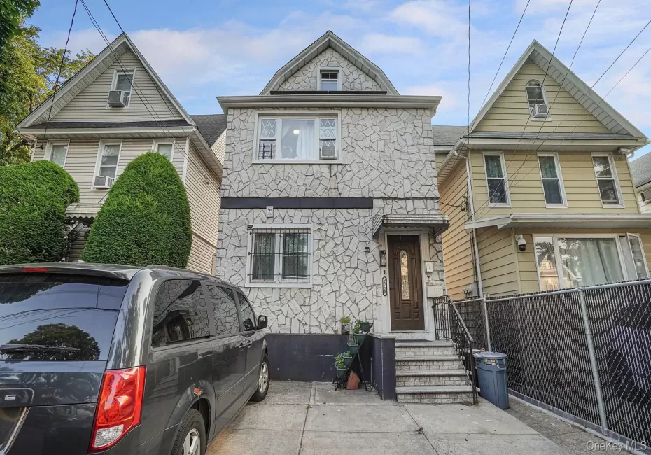 Two-story residence featuring stone-veneer cladding, a gabled roofline, concrete driveway, and covered front entryway with tiled steps Two-story residence featuring stone-veneer cladding, a gabled roofline, concrete driveway, and covered front entryway with tiled steps