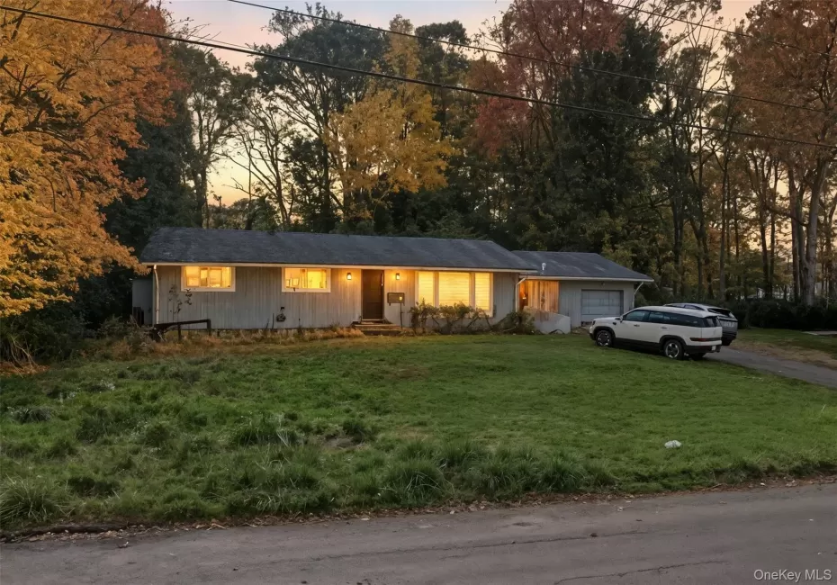 Ranch-style house with an attached garage, driveway, a lawn, and board and batten siding Ranch-style house with an attached garage, driveway, a lawn, and board and batten siding