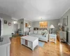 Expansive living area featuring wood-finish flooring, light gray wall tones, and white crown molding Expansive living area featuring wood-finish flooring, light gray wall tones, and white crown molding