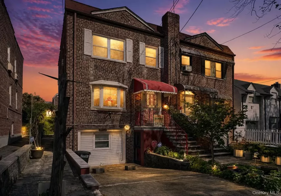 Brick facade residence featuring a prominent bay window with white shutters, a red alluminum awning, and a stone-lined planter bed Brick facade residence featuring a prominent bay window with white shutters, a red alluminum awning, and a stone-lined planter bed