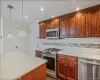 Kitchen featuring stainless steel appliances, hanging light fixtures, recessed lighting, tasteful backsplash, and light stone countertops Kitchen featuring stainless steel appliances, hanging light fixtures, recessed lighting, tasteful backsplash, and light stone countertops