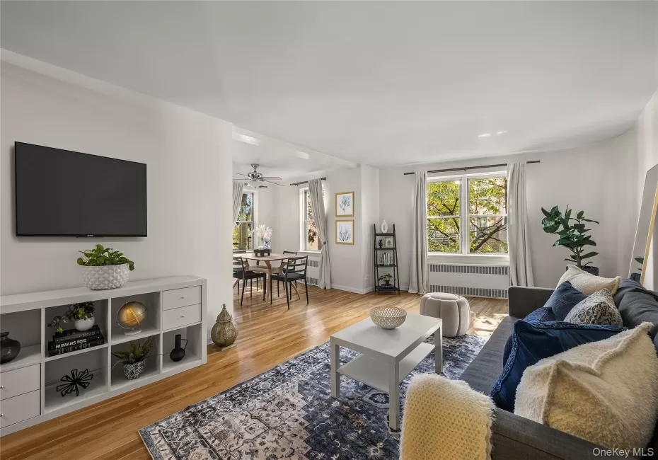 Living room with radiator, plenty of natural light, light wood-type flooring, and ceiling fan Living room with radiator, plenty of natural light, light wood-type flooring, and ceiling fan