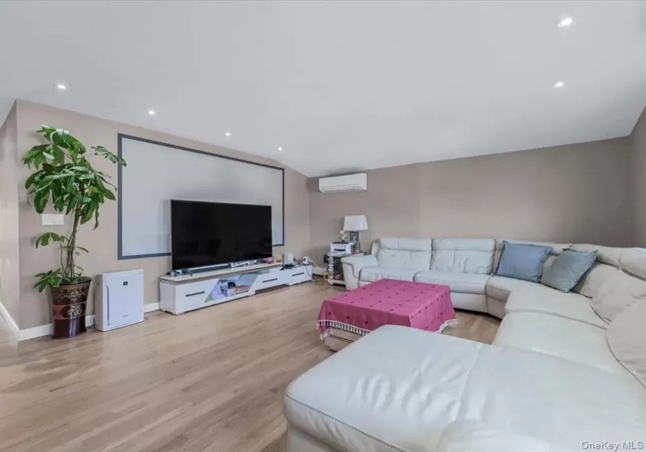 Living area featuring light wood-type flooring, recessed lighting, a wall mounted air conditioner, and vaulted ceiling Living area featuring light wood-type flooring, recessed lighting, a wall mounted air conditioner, and vaulted ceiling